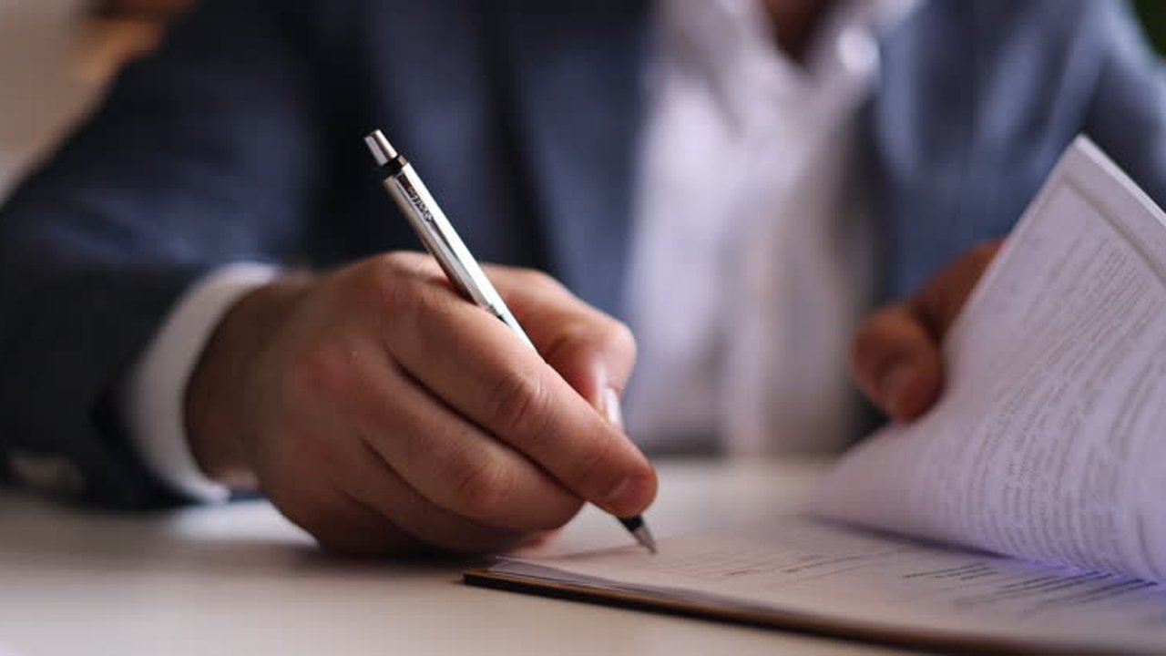 Contrato de encargo de tratamiento de datos sobre una mesa junto a la pantalla de una herramienta de inteligencia artificial